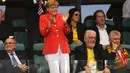 Kanselir Jerman, Angela Merkel (tengah) berdiri memuji permainan Philipp Lahm dkk saat berlaga di babak penyisihan Piala Dunia 2014 Grup G di Fonte Nova Arena, Brasil, (16/6/2014). (AFP PHOTO/Fabrice Coffrini)