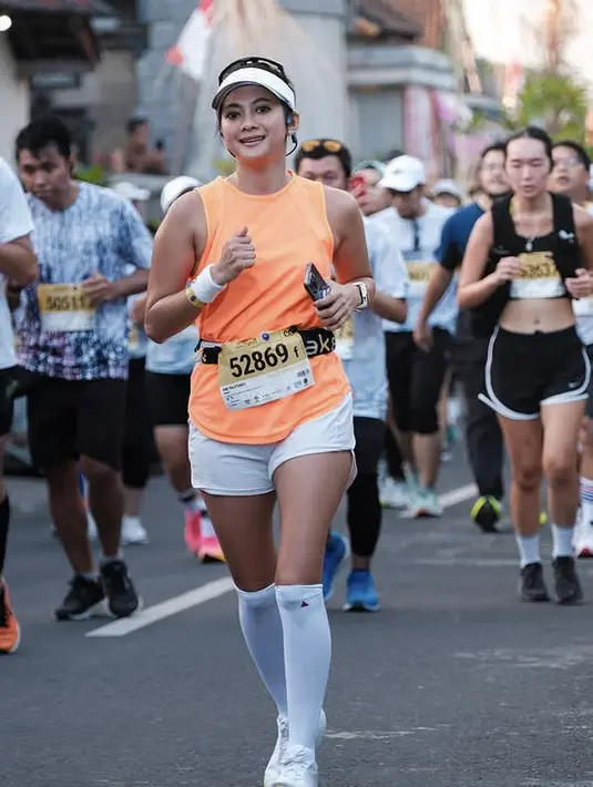Rini Yulianti tampil mengenakan atasan tanpa lengan warna orange dipadukan celana pendek putih serasi dengan sepatu lari, kaos kaki panjang, dan topinya. [@riniyulianti]