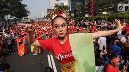 Seorang penari diikuti ribuan peserta membawakan Tari Puspanjali dari Bali saat CFD di Senayan, Jakarta, Minggu (12/8). Kegiatan ini digelar menyambut HUT Ke-73 RI dan Asian Games 2018. (Liputan6.com/Fery Pradolo)