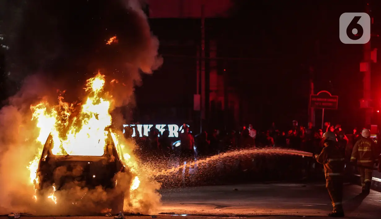 Petugas pemadam kebakaran memadamkan senuah mobil yang terbakar di Jalan Asia Afrika, Jakarta, Kamis (18/3/2021) dinihari. Diduga penyebab api adalah akibat dari hubungan pendek arus listrik yang terjadi di bagian mesin. (Liputan6.com/Johan Tallo)