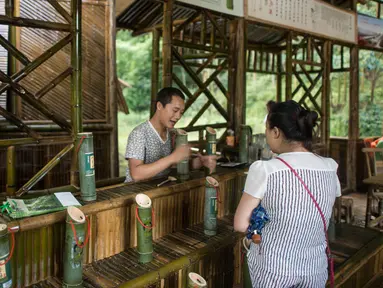 Pengunjung memesan minuman alkohol yang disimpan di dalam batang bambu di Hutan Yibin, China pada 30 Juli 2016. Minuman hasil frementasi biasanya disimpan di tong kayu, namun berbeda dengan minuman beralkohol buatan Chen Chao. (AFP Photo/Fred Dufour)