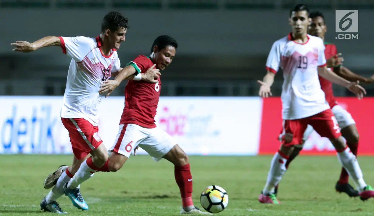 Gelandang Indonesia U-23, Evan Dimas Darmono (tengah) berebut bola dengan pemain Bahrain pada laga PSSI Anniversary 2018 di Stadion Pakansari, Kab Bogor, Jumat (27/4). Babak pertama Indonesia tertinggal 0-1. (Liputan6.com/Helmi Fithriansyah)