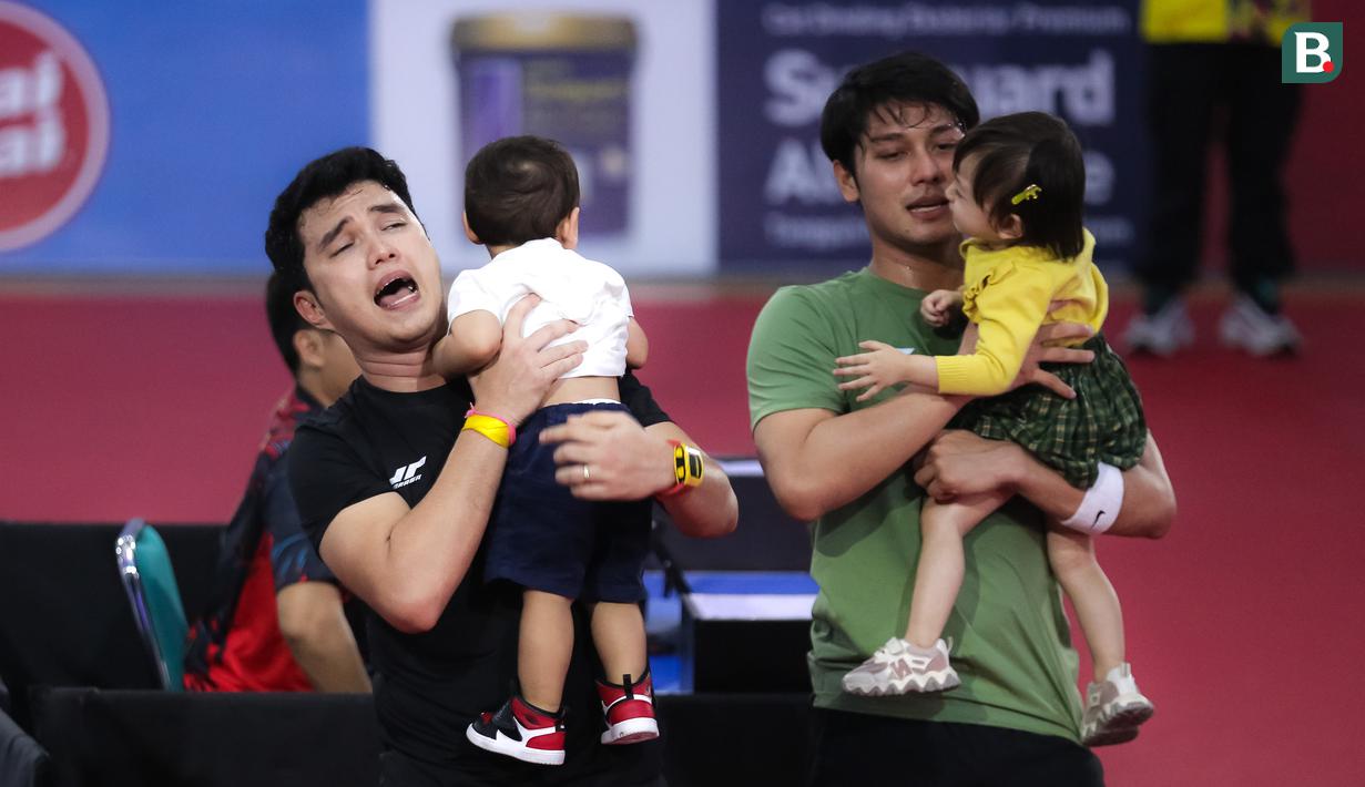 Selebritas Aldi Taher dan Rizky Billar saling bertukaran untuk menggendong anak mereka setelah laga tenis meja Turnamen Olahraga Selebriti Indonesia (TOSI) di GOR UNJ, Jakarta, Minggu (16/07/2023). Aldi Taher kalah tiga set langsung dari Rizky Billar dengan skor 12-21, 15-21, 11-21. (Bola.com/Bagaskara Lazuardi)