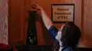 Seorang pelanggan memasukan token saat mengunjungi bar anti-Trump di New York City (25/4). Pemilik bar mengatakan bahwa mereka akan memberikan 100 persen keuntungan mereka kepada kelompok, berdasarkan jumlah token terbanyak. (AP Photo/Julie Jacobson)