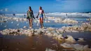 Wisatawan berjalan di antara busa pantai setelah siklon tropis di Currumbin Beach, Gold Coast, Australia pada 15 Desember 2020. Hujan lebat dan angin kencang telah melanda kawasan perbatasan padat penduduk antara New South Wales dan Queensland selama tiga hari. (Photo by Patrick HAMILTON / AFP)