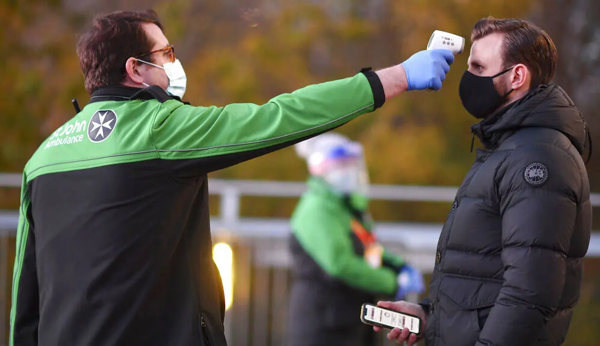 SUPORTER DIUKUR SUHU TUBUHNYA: Petugas memeriksa suhu tubuh suporter West Ham United sebelum menyaksikan pertandingan melawan Manchester United di Stadion London, Sabtu (5/12/2020). (Justin Setterfield/Pool Via AP)