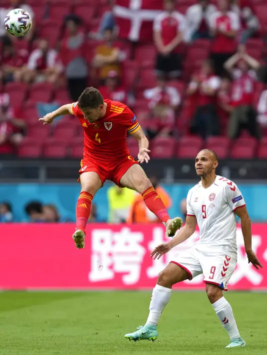Pemain Denmark Martin Braithwaite (kanan) menyaksikan pemain Wales Ben Davies melompat untuk merebut bola pada pertandingan babak 16 besar Euro 2020 di Johan Cruyff Arena, Amsterdam, Belanda, Sabtu (26/6/2021). Denmark menang 4-0. (AP Photo/Peter Dejong, Pool)