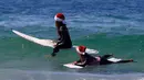 Dua wisatawan asal Jerman mengenakan topi Natal bersiap bermain surfing di Bondi Beach Sydney pada Hari Natal di Australia, (25/12). (REUTERS/David Gray)