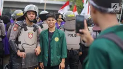 Seorang mahasiswa berfoto dengan polisi yang mengamankan aksi unjuk rasa Badan Eksekutif Mahasiswa Seluruh Indonesia (BEM SI) di sekitar gedung DPR RI, Jakarta, Selasa (1/10/2019). (Liputan6.com/Immanuel Antonius)