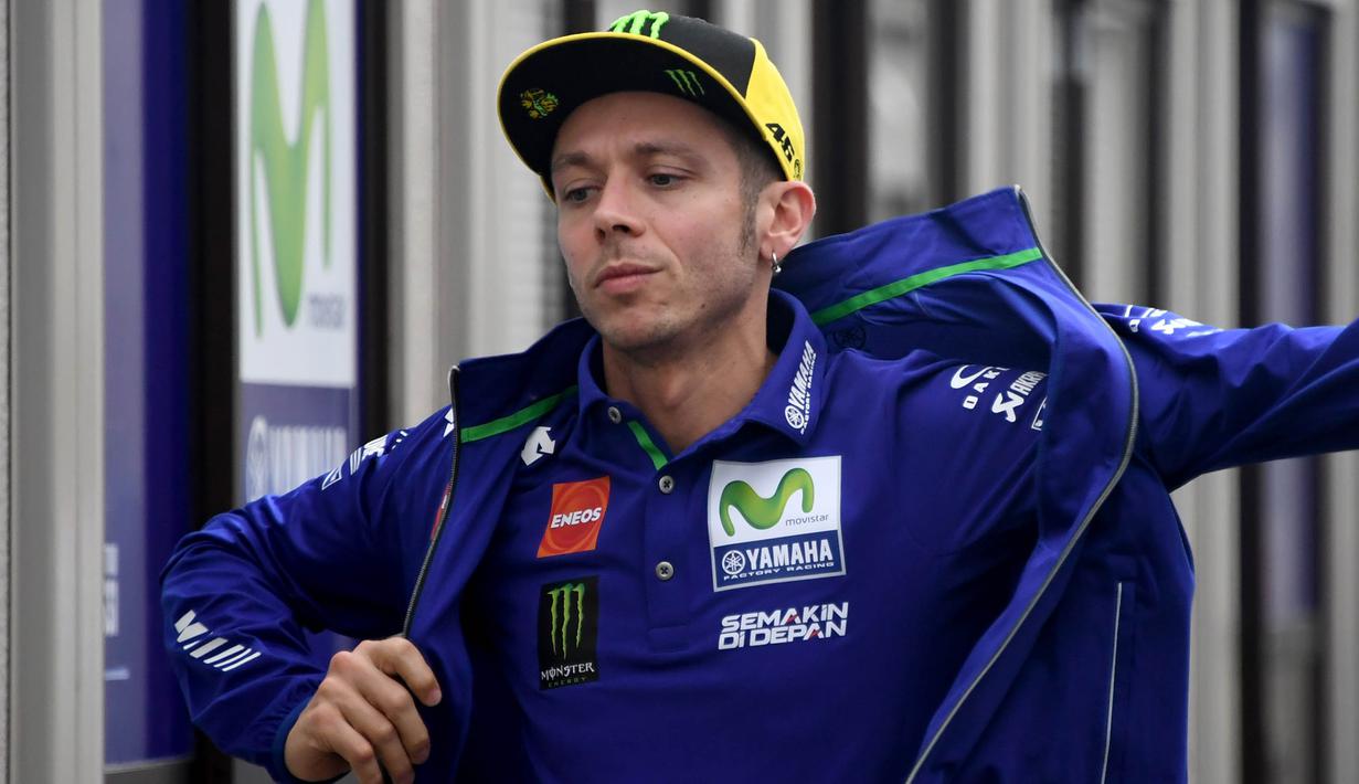 Pebalap Yamaha Movistar, Valentino Rossi, merapihkan jaket saat mendatangi paddock di Sirkuit Motegi, Tochigi Prefecture, Kamis (12/10/2017). MotoGP Jepang akan bergulir pada Minggu ini. (AFP/Toshifumi Kitamura)