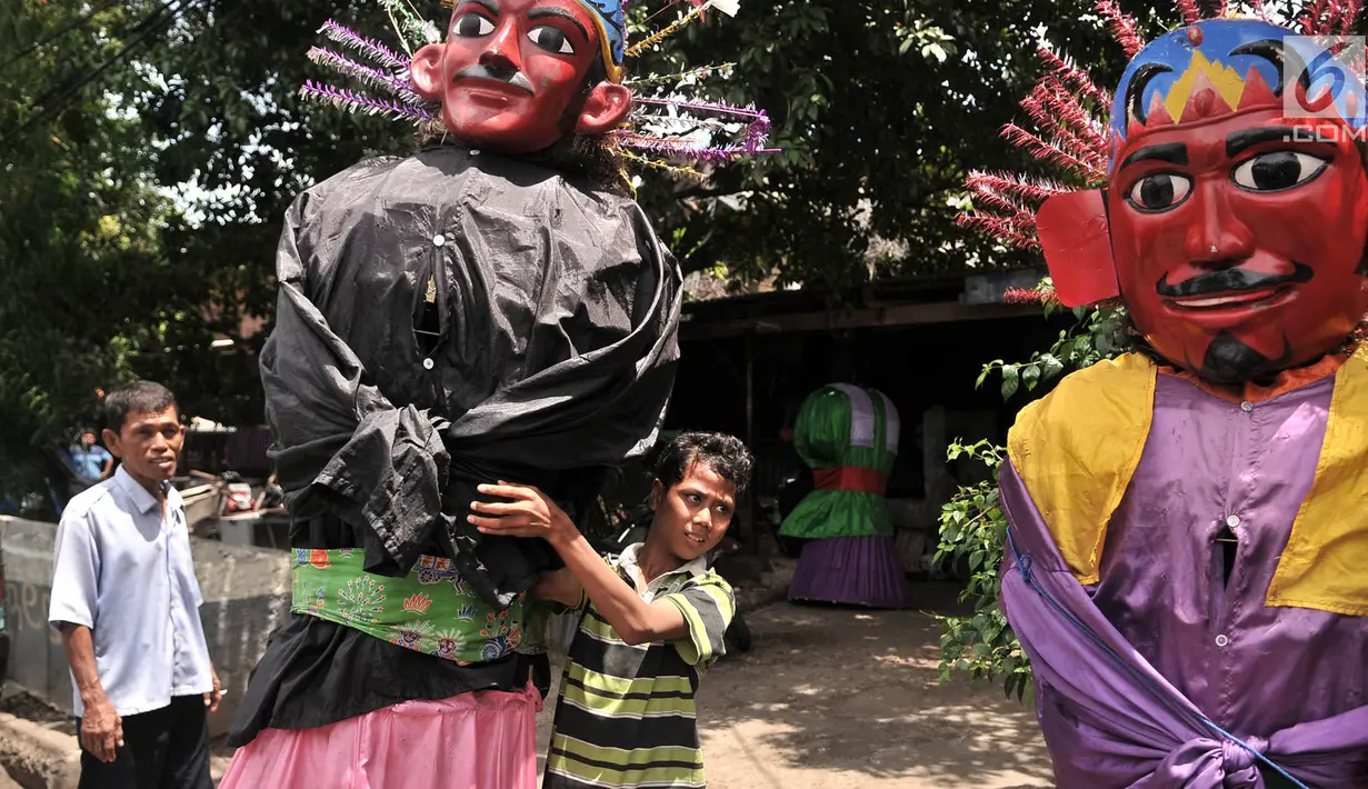 Seorang anak menggendong ondel-ondel saat bersiap untuk mengamen di kawasan Senen, Jakarta, Kamis (27/12). Hanya pengamen ondel-ondel beperalatan lengkap yang diperbolehkan. (Merdeka.com/Iqbal S. Nugroho)