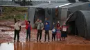 Anak-anak melambaikan tangan dekat tenda pengungsian mereka yang kebanjiran di Kamp Cordoba, Batabu, Idlib, Suriah, Rabu (16/1). Hujan badai membuat kamp pengungsian mereka kebanjiran. (Aaref Watad/AFP)