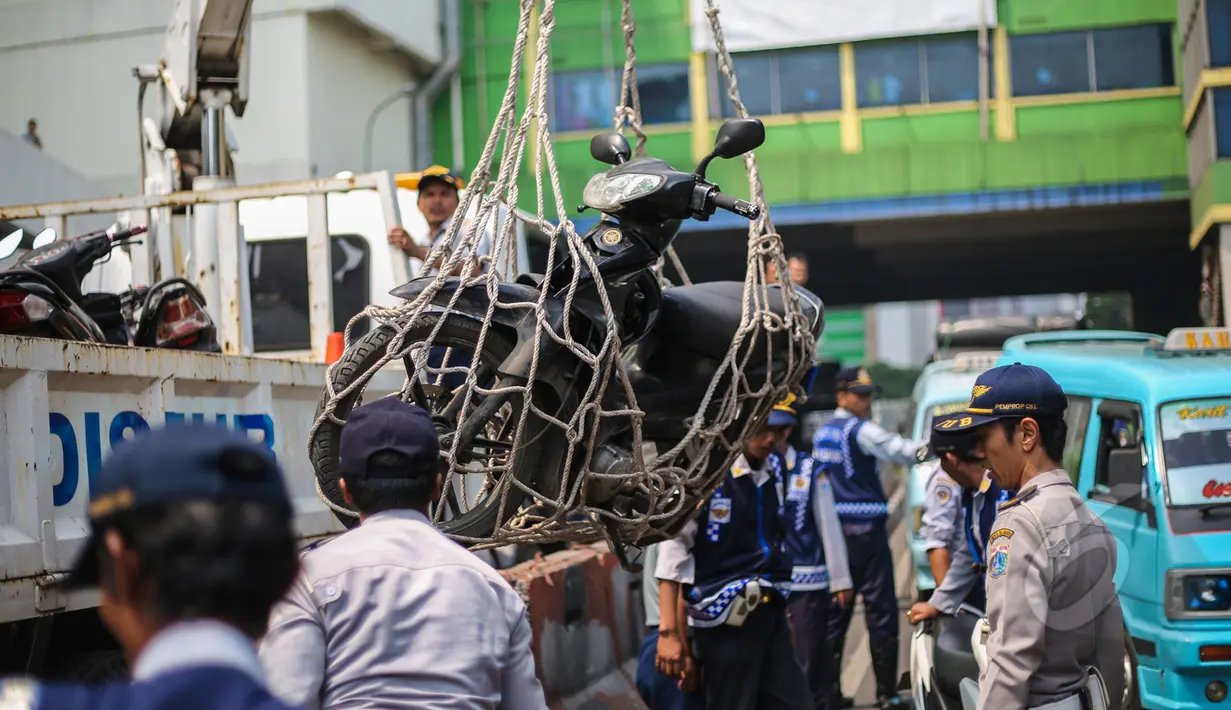 Petugas Dishub mengangkut sepeda motor dengan jaring saat razia parkir liar di kawasan Pasar Tanah Abang, Jakarta, Kamis (16/4/2015). Razia dilakukan untuk menciptakan kawasan yang tertib serta nyaman di kawasan Tanah Abang. (Liputan6.com/Faizal Fanani)