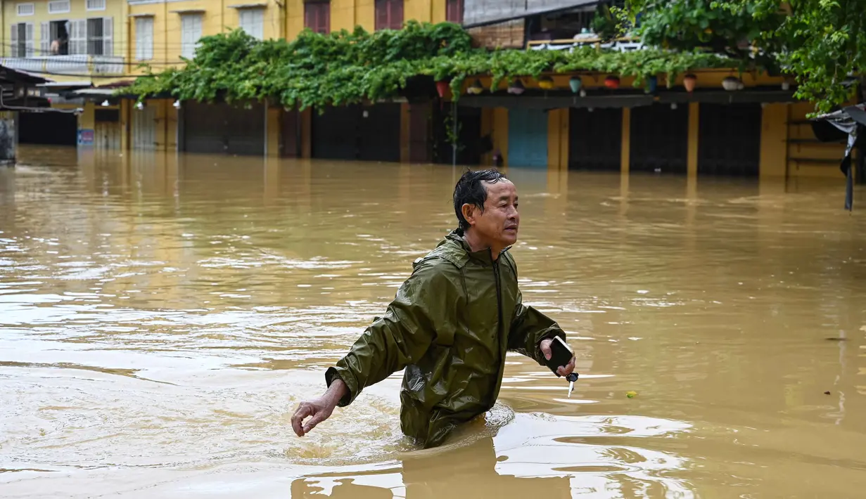 Seorang pria mengarungi jalan yang terendam banjir setelah hujan deras di Hoi An, Vietnam, Kamis 30 Oktober 2025. Permukiman warga di sebagian besar wilayah Hoi An terendam air, beberapa di antaranya bahkan hingga atap. (NHAC NGUYEN/AFP)