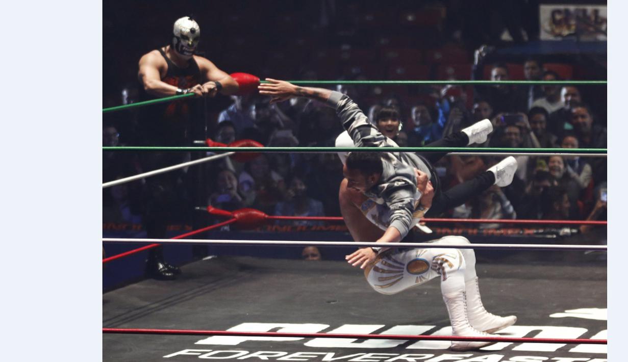 Pebalap F1 dari tim Mercedes GP, Lewis Hamilton berusaha menjatuhkan pegulat yang bintang WWE di Coliseo Arena, Mexico City, (28/10/2015). (Reuters/Henry Romero)