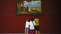 Keluarga melihat lukisan minyak di atas kanvas yang berjudul "Upacara Pendirian Tiongkok" oleh Dong Xiwen, ketika mereka mengunjungi Museum Nasional Cina di Beijing (22/8/2019). Museum ini dibangun oleh Kementerian Kebudayaan Republik Rakyat Tiongkok. (AFP Photo/Wang Zhao)
