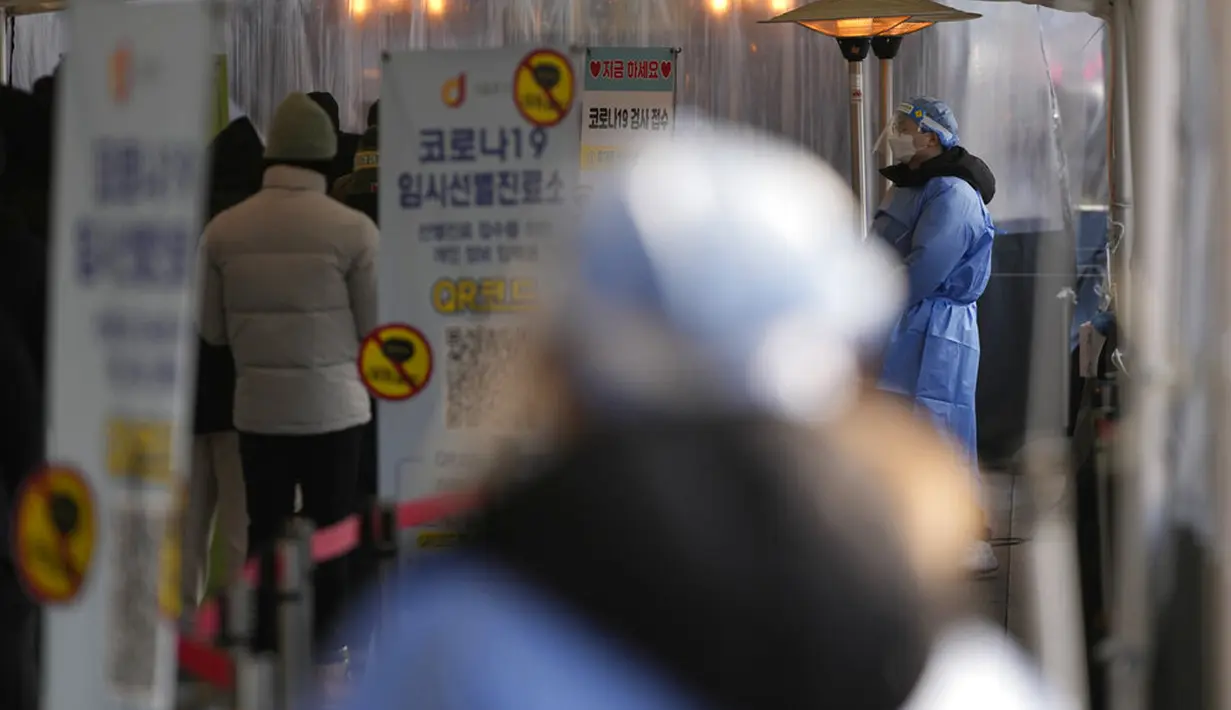 Petugas kesehatan yang mengenakan alat pelindung diri berdiri untuk membantu pengunjung di klinik skrining sementara untuk virus corona dekat Balai Kota Seoul, Seoul, Korea Selatan, Rabu (26/1/2022). (AP Photo/Lee Jin-man)