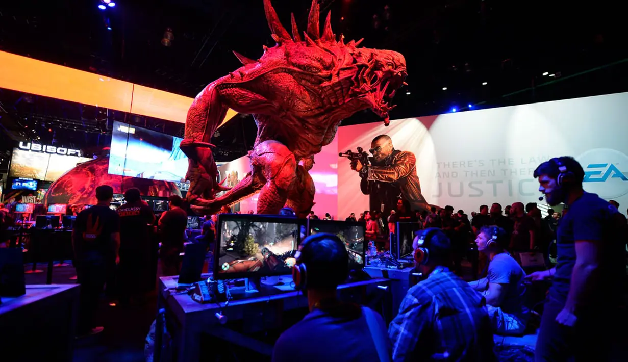 Di bawah patung raksasa Goliath, para pengunjung memainkan video game baru "Evolve" yang ikut dipamerkan dalam Electronic Entertainment Expo (E3), di Los Angeles, Amerika Serikat, (10/6/2014). (REUTERS/Kevork Djansezian)