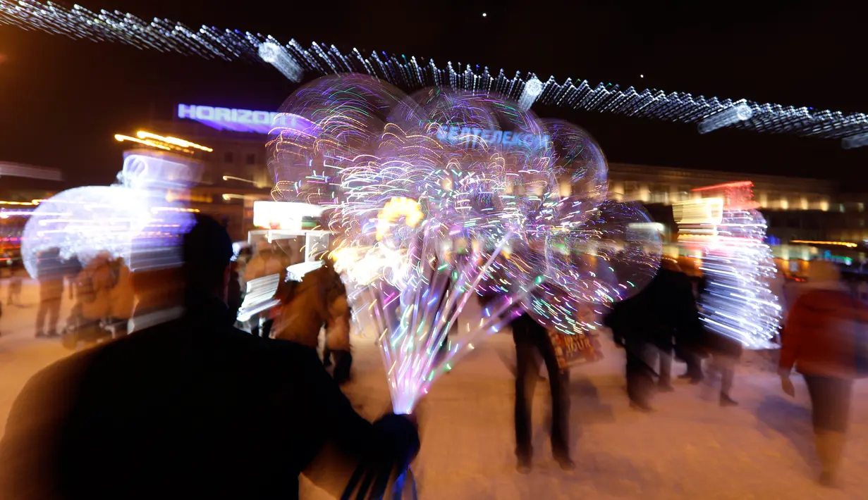 Seorang pedagang menjajakan balon kepada pengunjung di alun-alun yang didekorasi menyambut perayaan Natal 2018 dan Tahun Baru 2019 di Minsk, Belarus, Selasa (18/12). (AP Photo/Sergei Grits)