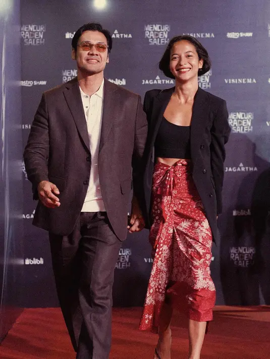 Menghadiri red carpet, Putri Marino berpose bersama sang suami juga mengenakan kain sebagai bawahan. Tank top hitam yang dilapisi engan oversized blazer yang juga berwarna hitam menjadi semakin menarik ketika dipadu dengan kain merah dengan corak floral. Foto: Instagram.