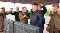 Pemimpin Korea Utara, Kim Jong-Un merayakan uji coba peluncuran rudal balistik Hwasong-12 di lokasi yang tak diketahui pada foto yang dirilis Sabtu (16/9). Rudal Hwasong-12 Korut pada Jumat ditembakkan menerobos langit Hokkaido Jepang (KCNA/KNS via AP)