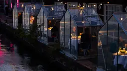 Pengunjung menikmati makanan mereka dalam kabin kaca berkonsep "quarantine greenhouses" selama uji coba, ketika Belanda berjuang melawan penyebaran COVID-19, di restoran Mediamatic, Amsterdam pada 5 Mei 2020. (AP/Peter Dejong)