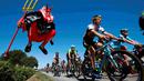 Pebalap sedang melewati Didi Senft, seorang penggemar balap sepeda yang dikenal dengan nama 'El Diablo' (The Devil) di Etape 7 Tour de France yang berjarak 190.5-km dari Livarot ke Fougeres, Prancis, (10/7/2015). (REUTERS/Eric Gaillard)