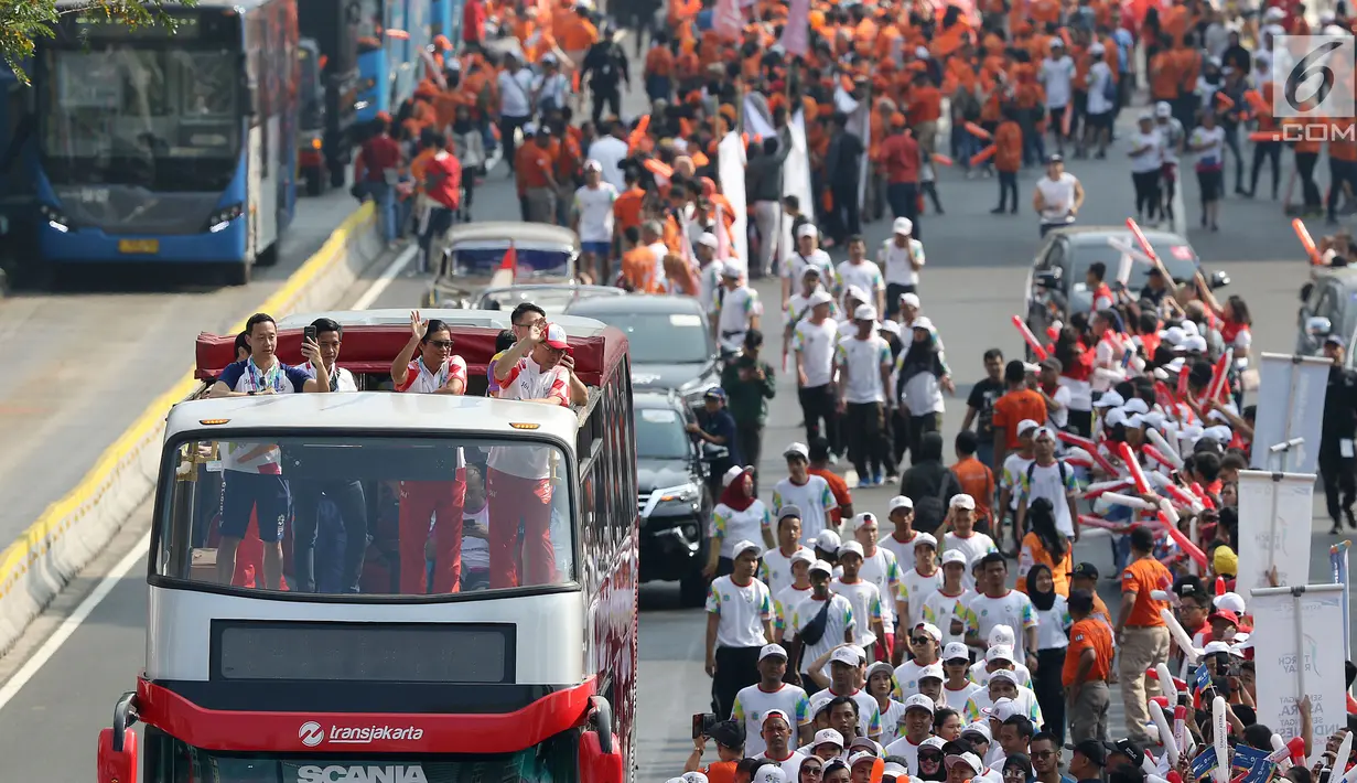 Bus tingkat dengan kap terbuka membawa pelari Torch Relay Asian Games 2018 di Jalan Jendral Sudirman, Jakarta, Sabtu (18/8). Hari terakhir kirab obor Asian Games ini api abadi dibawa dari Tugu Monas hingga Gelora Bung Karno. (Liputan6.com/ Fery Pradolo)
