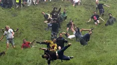 Sejumlah peserta berlari menuruni bukit curam untuk mengejar keju dalam kompetisi Cheese Rolling di Cooper's Hill di Brockworth, Gloucestershire, Inggris, Senin (28/5). Kompetisi ini diikuti ribuan peserta setiap tahunnya. (Aaron Chown/PA via AP)