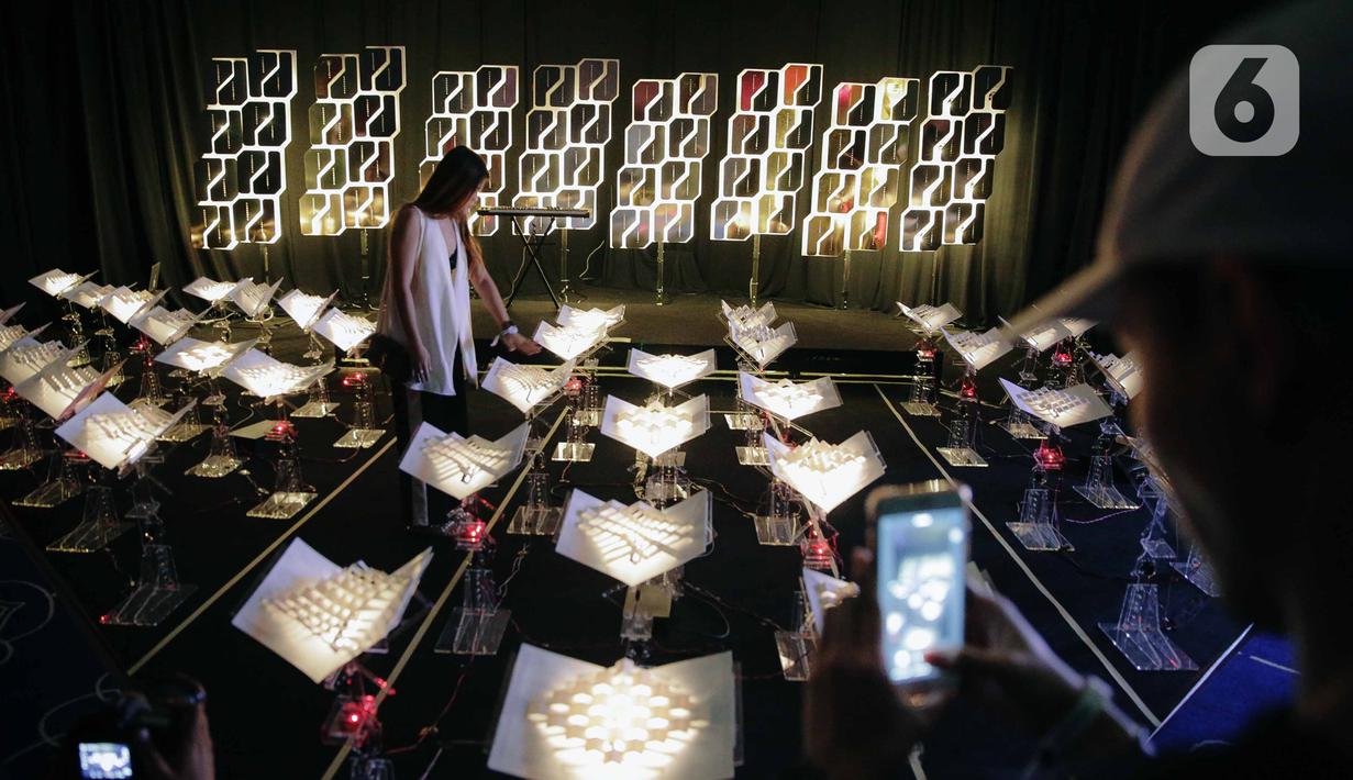 Pengunjung berpose saat mengunjungi pameran seni berbasis teknologi berwujud sorotan cahaya futuristik 'Wave of Tomorrow' di Jakarta, Sabtu (21/12/2019). Pameran seni Wave of Tomorrow menghadirkan 14 karya seni media baru dari 13 kreator Tanah Air dan internasional.  (Liputan6.com/Faizal Fanani)