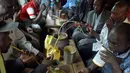 Sejumlah pria menggunakan selang kecil meminum air beralkohol dari pot yang disebut Busaa di daerah Nairobi, Kenya, Rabu (8/11). (AFP Photo/Simon Maina)