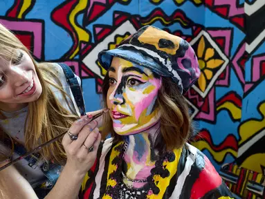 Seniman Alexa Meade (kiri) melukis wajah model Justine Jaime dalam instalasi seni 3D interaktif di Union Station, Los Angeles, Kamis (7/6). Acara ini digelar sebagai hiburan musim panas. (AP Photo/Richard Vogel)