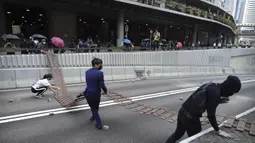 Demonstran menyeret pagar untuk menghalangi jalan selama protes di distrik keuangan di Hong Kong (14/11/2019). Warga Hong Kong mengalami hari keempat kemacetan lalu lintas dan gangguan angkutan massal ketika pengunjuk rasa menutup beberapa jalan utama dan jaringan kereta api.  (AP Photo/Vincent Yu)