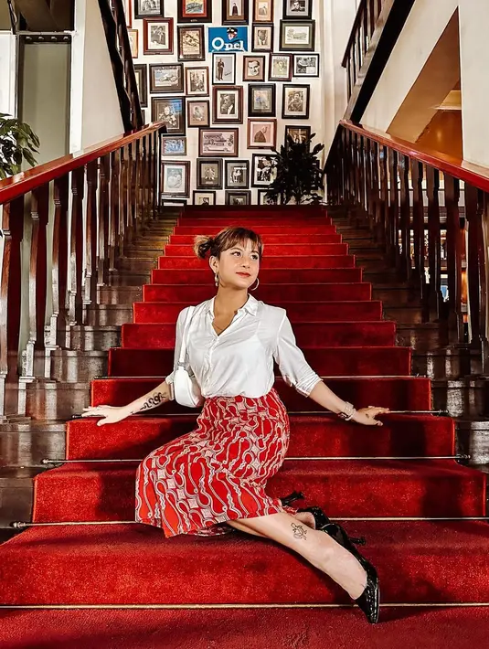 Tampil anggun dengan padu padan kemeja putih dan rok batik merah. Lengkapi gaya dengan pointed heels. [Instagram/narinkovilda]