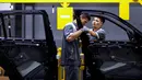 Pekerja memasang pintu saat merakit mobil di pabrik VinFast, Haiphong, Vietnam, Jumat (14/6/2019). VinFast akan memenuhi pasar domestik Vietnam di segmen sedan dan SUV kelas menengah. (Manan VATSYAYANA/AFP)