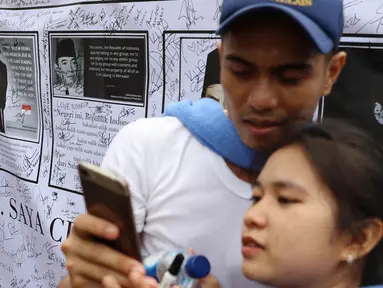 Warga membubuhkan tanda tangan di spanduk bergambar tokoh nasional di area car free day, Jakarta, Minggu (14/5). Kegiatan itu sebagai bentuk simpati terhadap kondisi nasional yang ramai akan isu perpecahan dan perbedaaan. (Liputan6.com/Immanuel Antonius)