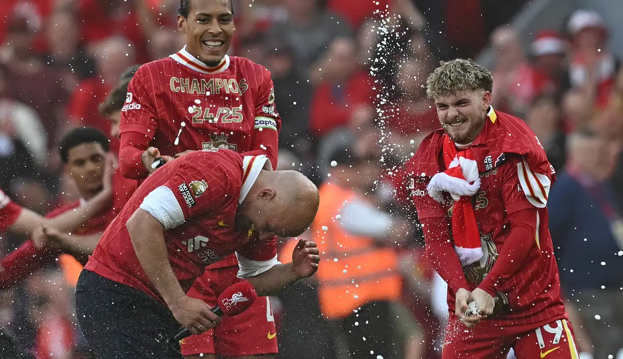 Pelatih Liverpool, Arne Slot dismprot oleh Harvey Eliott (kanan) dan Virgil van Dijk (kiri) saat merayakan gelar juara Liga Inggris 2024/2025 setelah mengalahkan Tottenham Hotspur di Anfield, Liverpool, Inggris, Minggu (27/04/2025). (AFP/Paul Ellis)