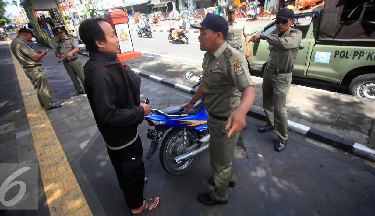 Petugas Satpol PP berdiskusi dengan seorang yang terkena razia yang parkir di kawasan pendestrian Malioboro, (19/4). Petugas memberikan surat peringatan dan mengambil kartu identitasnya yang di tahan di KUPT Malioboro. (Liputan6.com/Boy Harjanto)