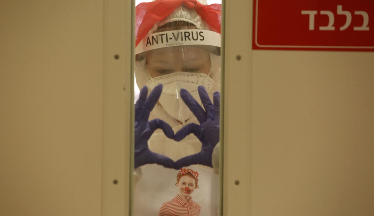 Badut medis yang memakai alat pelindung diri (APD) membuat tanda hati dengan jari tangannya sebelum mengunjungi pasien anak-anak di bangsal COVID-19 di Sheba Medical Center, Kota Ramat Gan, Israel, 20 Oktober 2020. (Xinhua/Gil Cohen Magen)