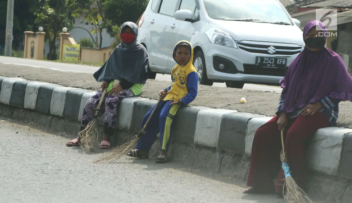 Seorang bocah penyapu koin kali Sewo menunggu di pinggir jalan, Subang, Jawa Barat, Sabtu (7/1). Selain bertambah banyak, kini warga yang mangkal juga dari berbagai kalangan usia, mulai anak-anak hingga dewasa. (Liputan6.com/Helmi Afandi)