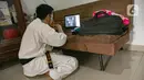 Charlie (28) instruktur karate menyaksikan para muridnya berlatih secara virtual di Jakarta, Sabtu (13/2/2021). Selama pandemi Covid-19 murid-murid berlatih setiap hari Sabtu sekitar 1.5 jam. (Liputan6.com/Faizal Fanani)