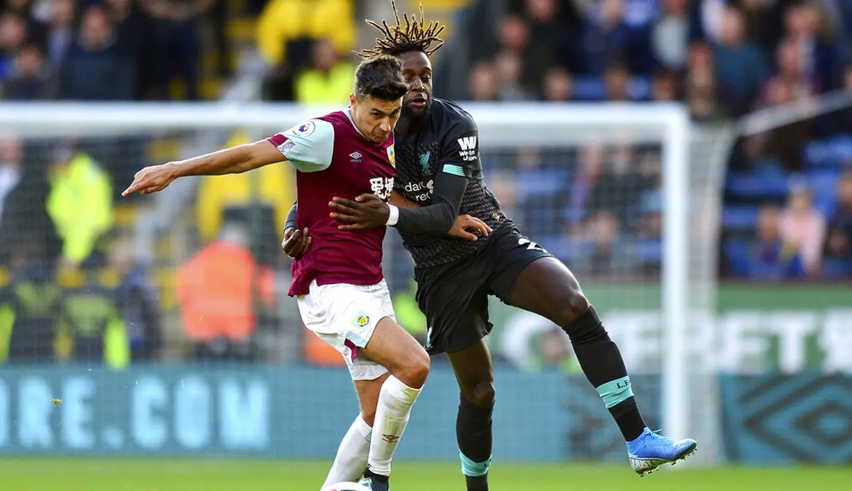 Penyerang Liverpool, Divock Origi, berebut bola dengan pemain Burnley, Matthew Lowton, pada laga Premier League 2019 di Stadion Turf Moor, Sabtu (31/8). Liverpool menang 3-0 atas Burnley. (AP/Anthony Devlin)