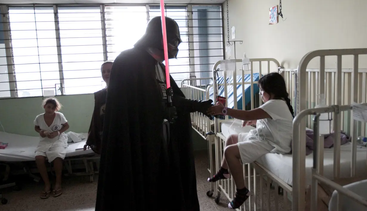 Seorang cosplayer berpakaian Darth Vader berbincang dengan seorang pasien saat acara amal oleh El Salvador Star Wars fan club di Rumah Sakit Benjamin Bloom Anak Nasional di San Salvador, El Salvador (14/12). (REUTERS/Jose Cabezas)