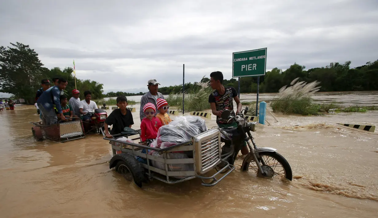 Warga naik ojek untuk menyeberangi banjir setelah hujan lebat di Kota Candaba, Pampanga, Manila, Filipina (17/12). Sembilan orang tewas akibat bencana yang terjadi di Filipina. (REUTERS/Romeo Ranoco)