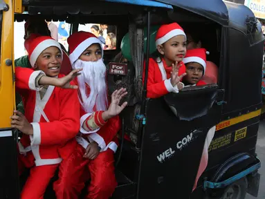 Anak-anak India mengenakan kostum Santa Claus menaiki Bajaj saat merayakan Natal di Jammu, India (22/12). Meskipun di India orang Kristen hanya 2 persen dari populasi, Natal di India cukup meriah. (AP Photo / Channi Anand)