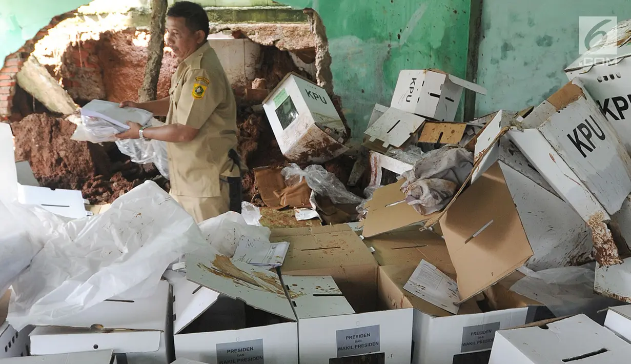 Petugas kecamatan menyelamatkan kotak suara kardus yang sebagian rusak terendam banjir di gudang tempat penyimpanan logistik di Kecamatan Ciseeng, Bogor, Senin (15/4). Lebih dari 600 kotak suara rusak akibat tembok gudang jebol diterpa hujan lebat dan angin kencang semalam. (merdeka.com/Arie Basuki)