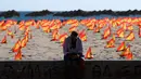 Seorang pria duduk di dekat ribuan bendera Spanyol yang mewakili korban COVID-19 di negara itu dipasang di pantai Patacona, Valencia pada Minggu (4/10/2020). Virus corona di Spanyol sejauh ini telah merenggut lebih dari 32.000 nyawa dan 790.000 kasus terkonfirmasi. (Jose Jordan / AFP)