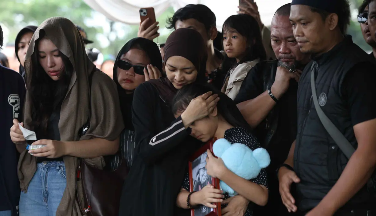 Jenazahnya dimakamkan pada hari yang sama di TPU Tanah Kusir, Jakarta Selatan. Tampak dalam foto, istri Gary Iskak, Richa Novisha (tengah) memeluk anaknya saat berada di dekat pusara sang suami di Taman Pemakaman Umum (TPU) Tanah Kusir, Jakarta Selatan, Sabtu (29/11/2025). (Kapanlagi.com/Budy Santoso)