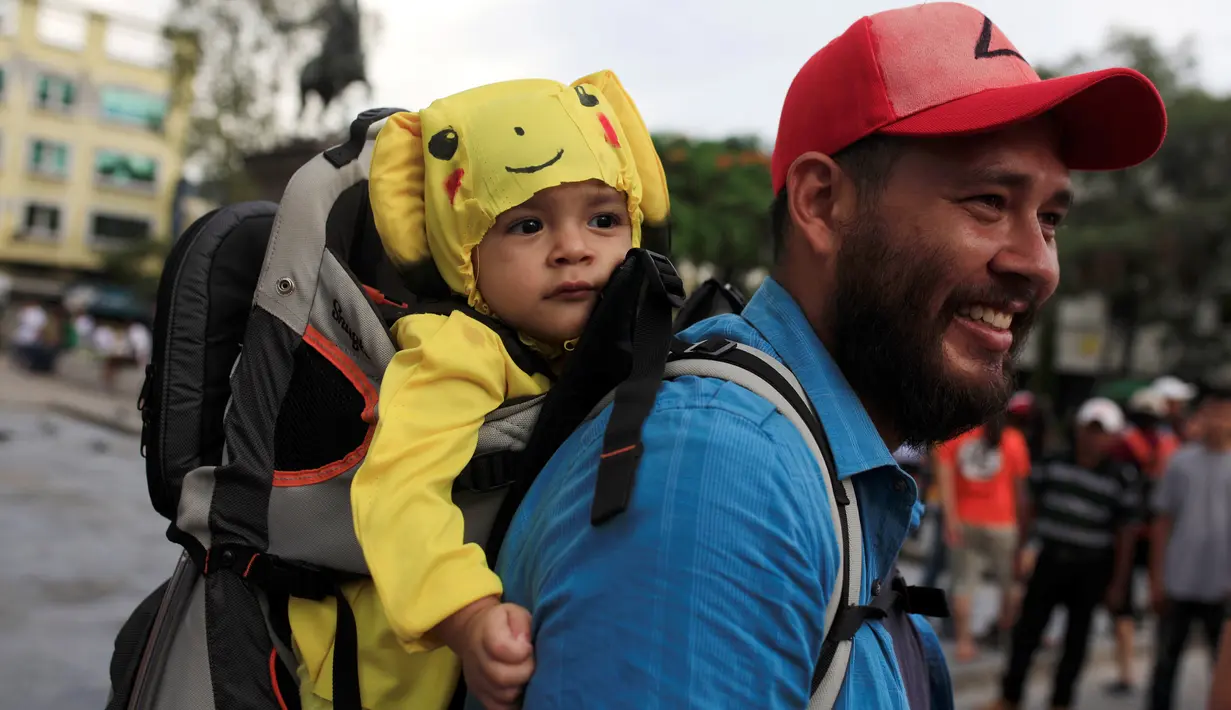 Seorang balita dipakaikan kostum karakter dari game augmented reality Pokemon Go ketika berpatisipasi dalam acara "poketour" di San Salvador, El Salvador, Sabtu (23/7). (REUTERS/Jose Cabezas)
