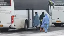 Petugas medis mengawal seorang pria memasuki bus setelah dievakuasi dari Wuhan di sebuah bandara luar Tyumen, Rusia, Rabu (5/2/2020). Rusia mengevakuasi 144 orang dari Wuhan yang terdiri dari warga Rusia, Belarus, Ukraina, dan Armenia menyusul wabah virus corona. (AP Photo/Maxim Slutsky)